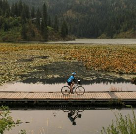Biker on pond on Trail of the Coeur d’Alenes tour